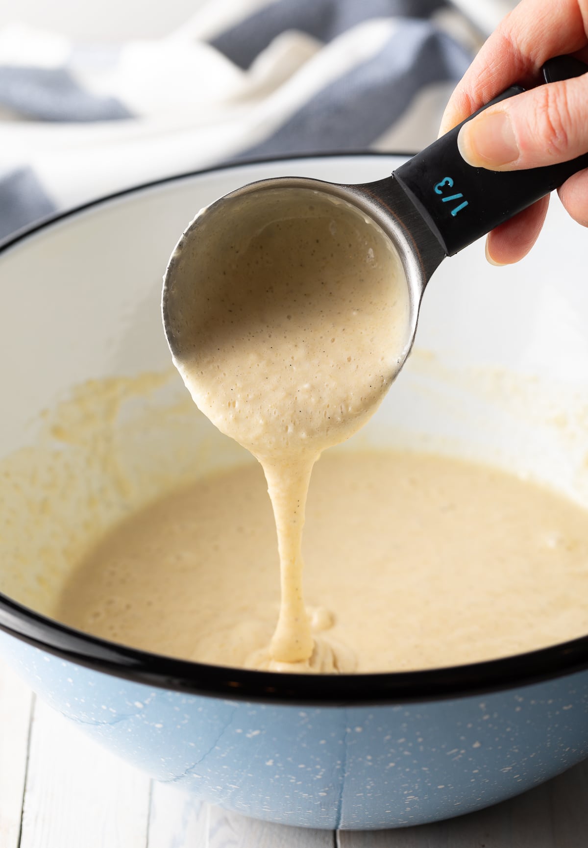 Batter being scooped into a measuring cup. 