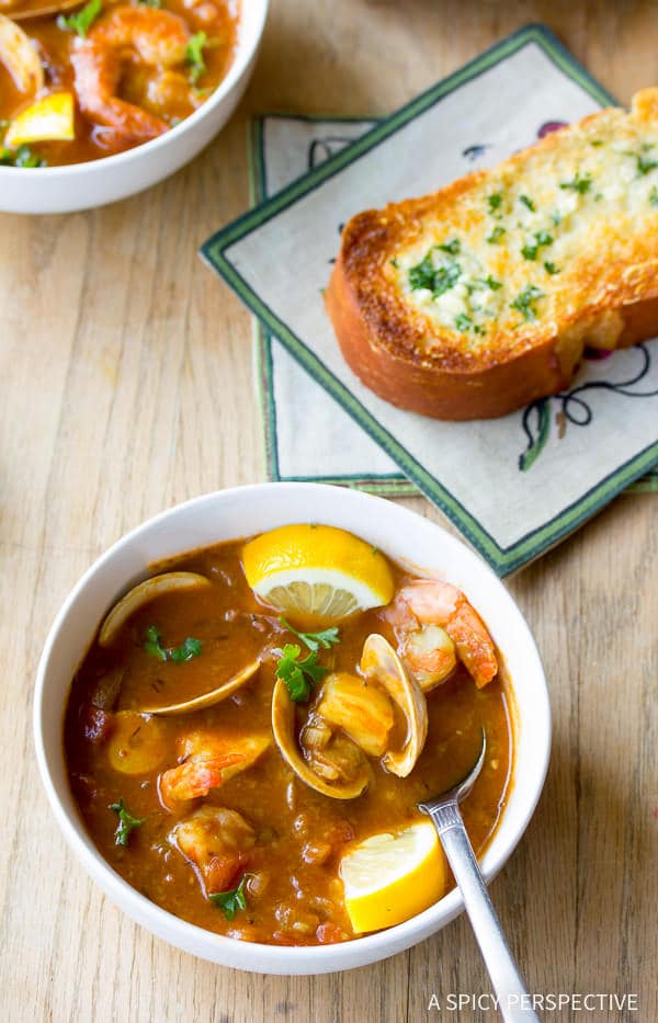 Cioppino soup in white bowls with shrimp and clams
