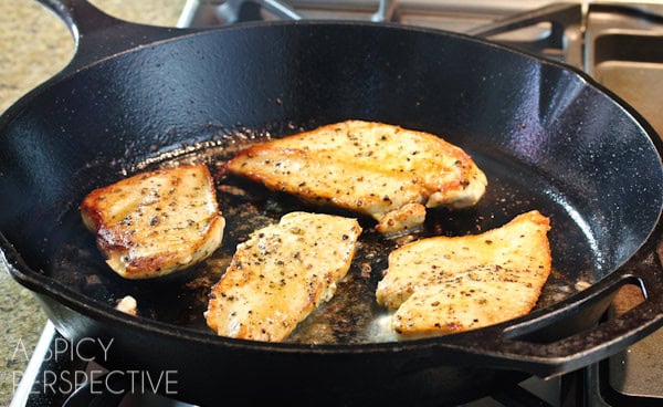 Chicken cutlets being sautéed in a cast iron skillet. 