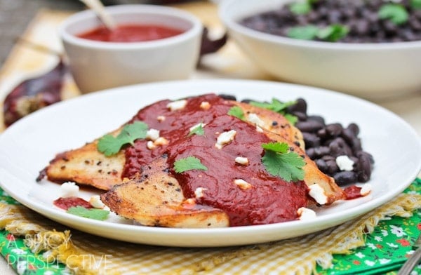 Pollo rojo (red pepper chicken) served on a plate with black beans. 