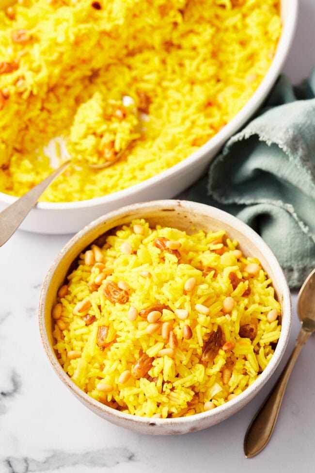 Easy Saffron Rice with Golden Raisins and Pine Nuts #vegan #glutenfree #recipes A white bowl of saffron and raisin rice.