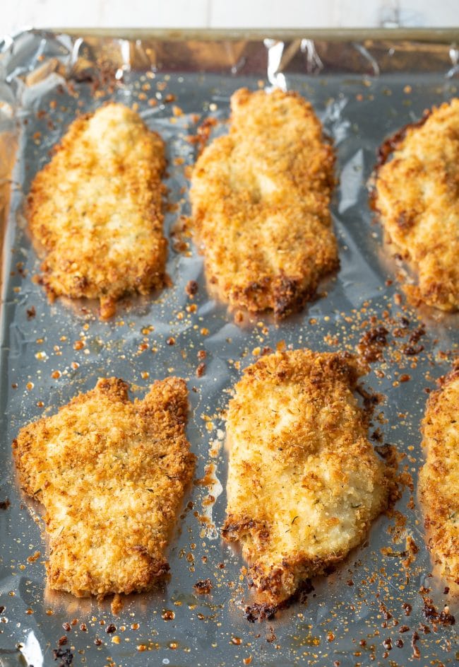 Overhead shot of crispy baked chicken cutlets on a baking tray. 