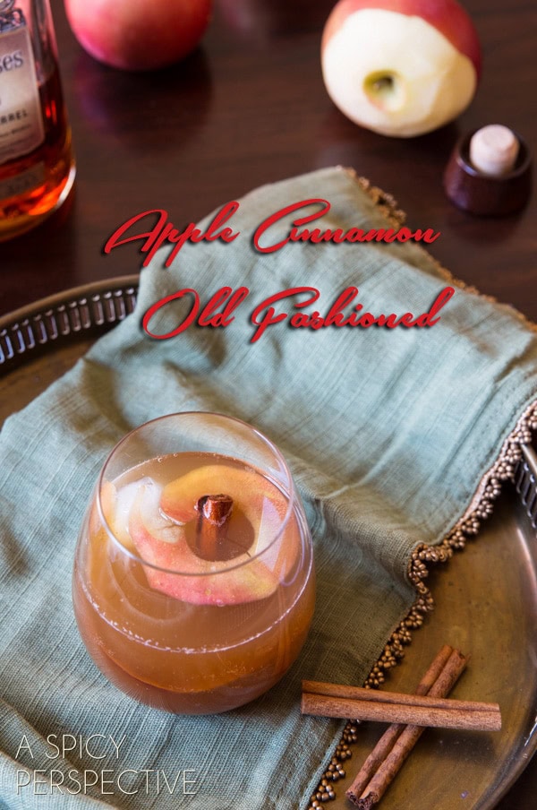 Cocktail with cinnamon sticks next to it and text saying "apple cinnamon old fashioned". 