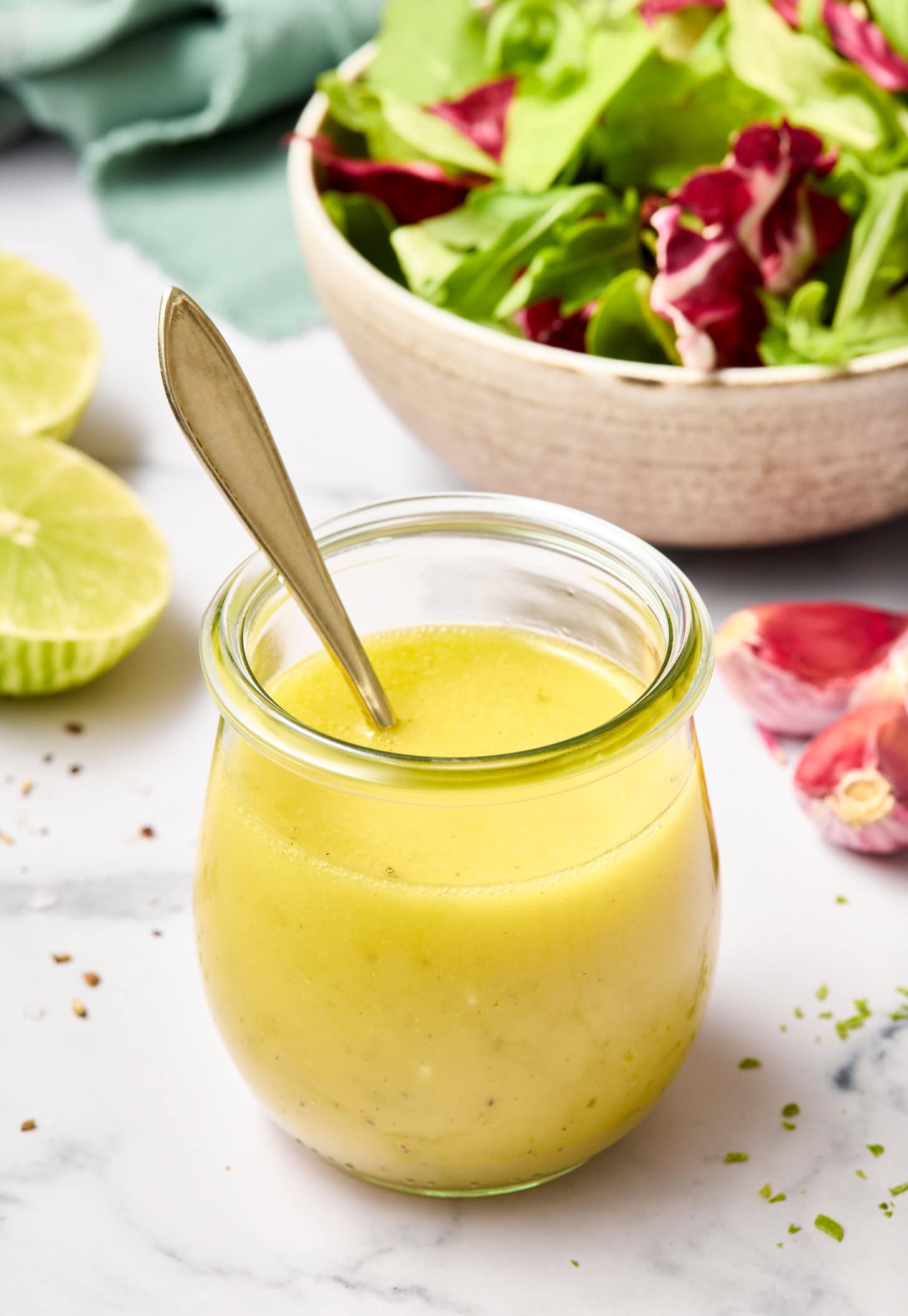 A honey lime vinaigrette recipe in a glass jar with a spoon in it.