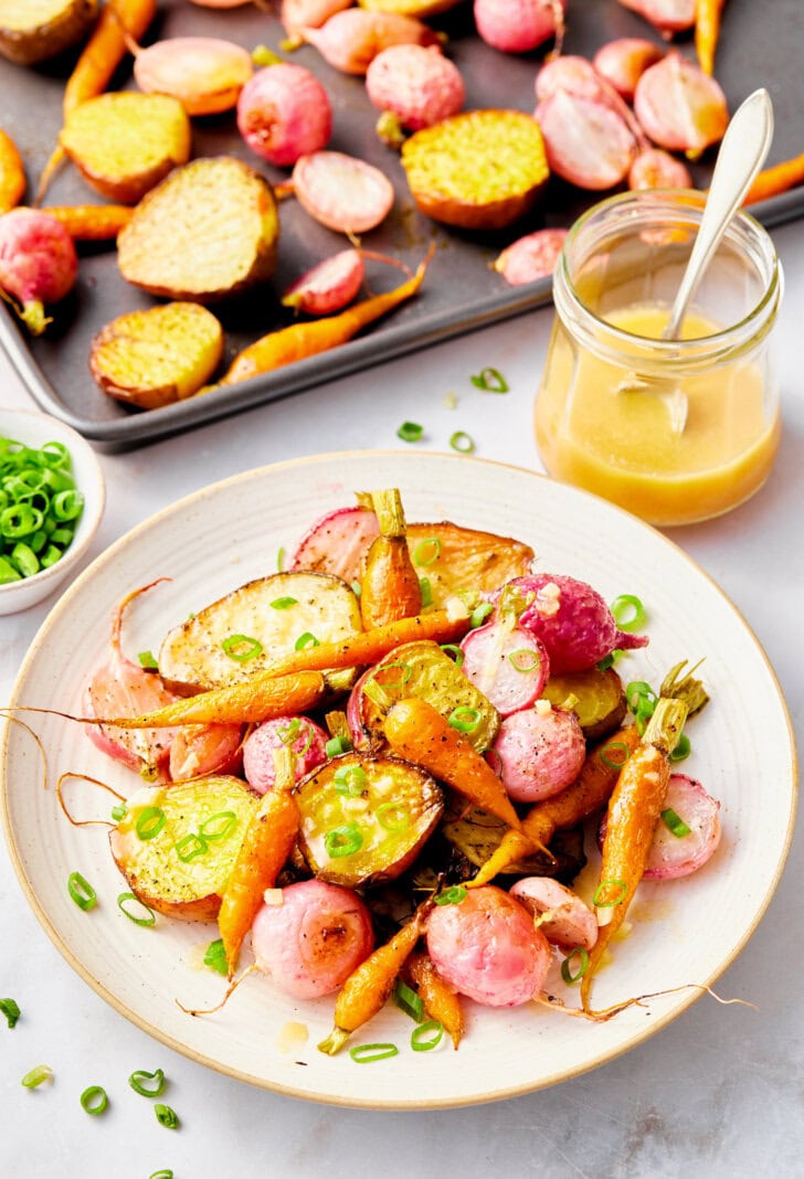 Roasted vegetables on a plate with sheet pan in background