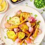 Roasted root vegetables on a sheet pan with a spatula.