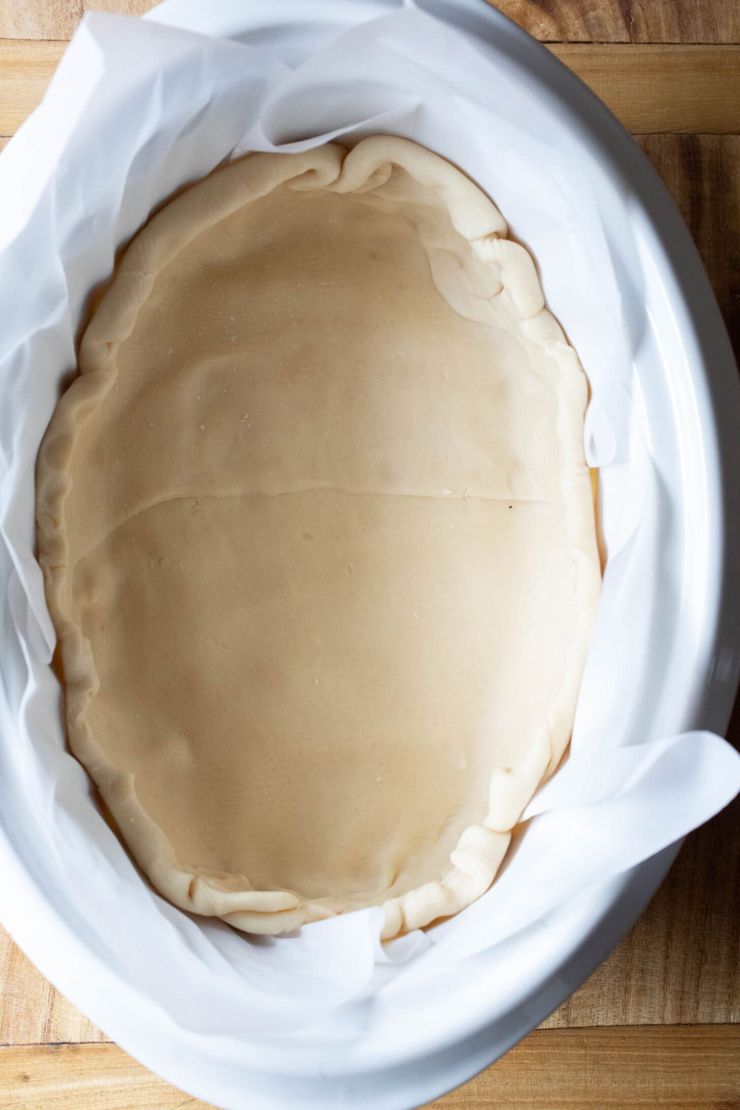 Top down shot of pie dough spread into the crockpot.