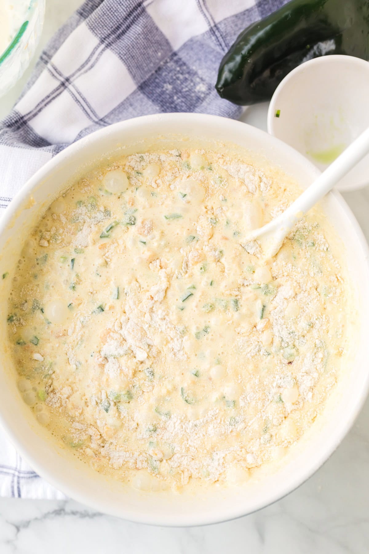 Top view of a bowl with the batter for the pudding and a spoon to stir it together 
