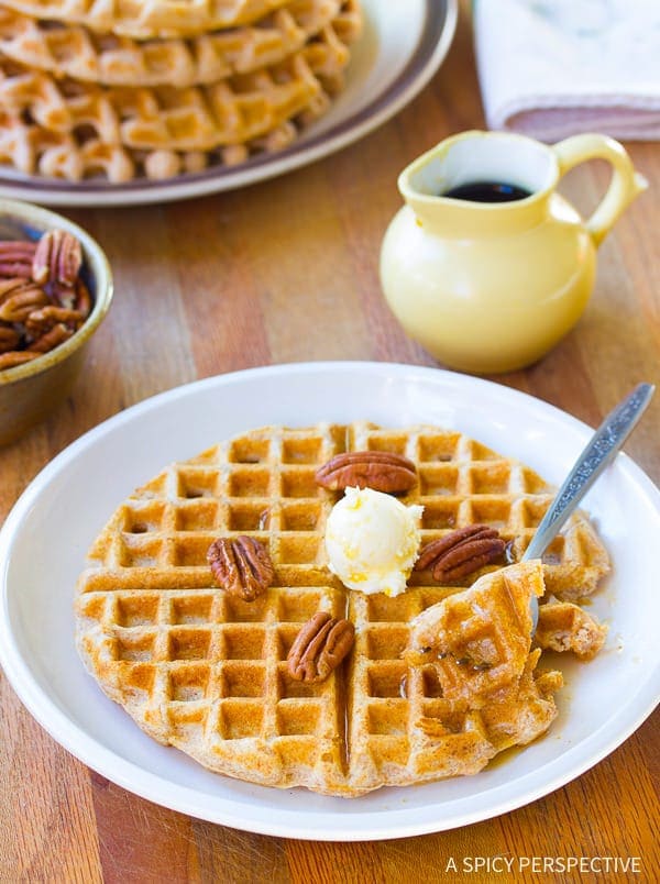 Healthy Spelt Flour Waffles stacked on plate with nuts and syrup
