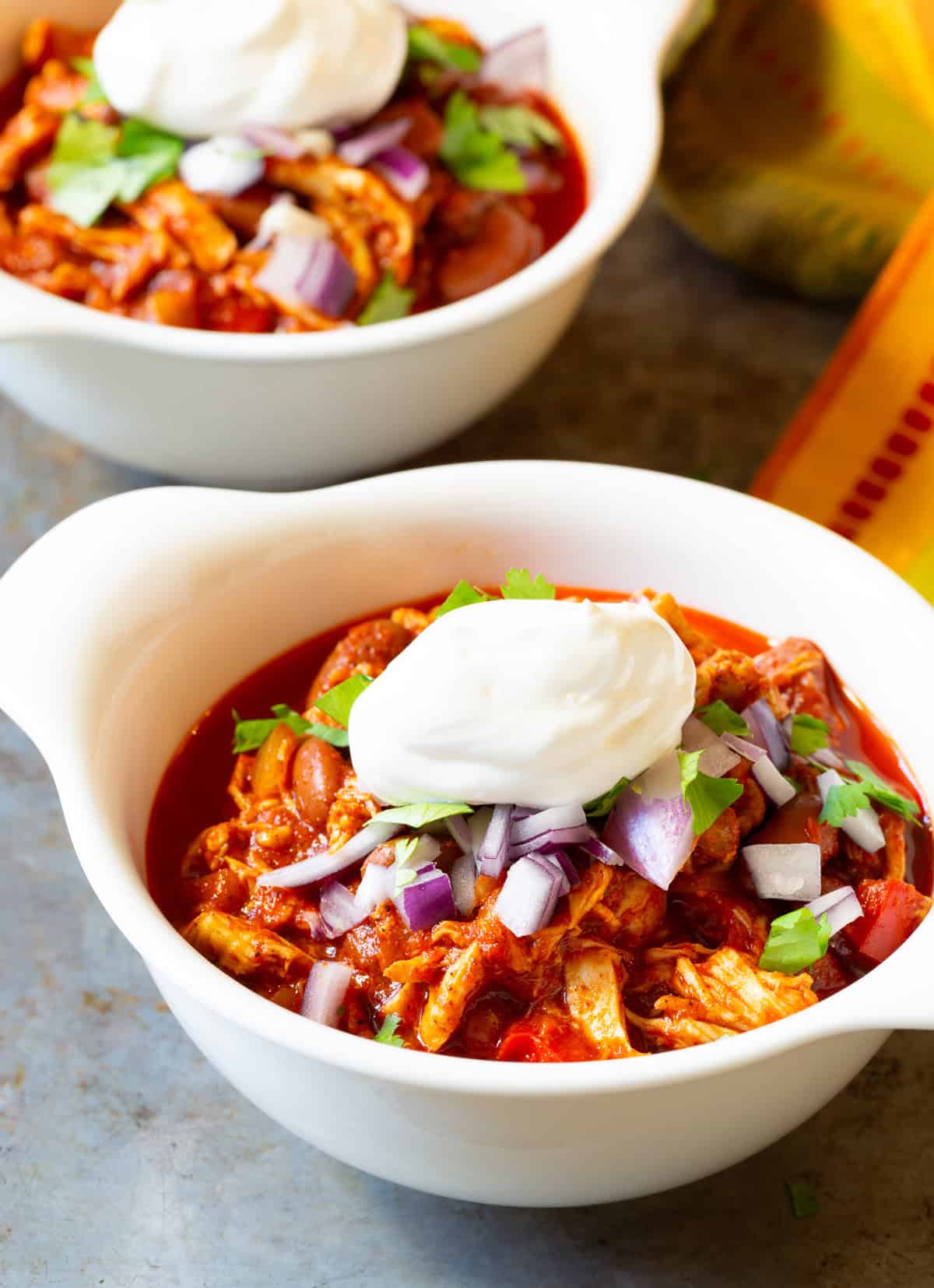 roasted red pepper chili in two white bowls with toppings