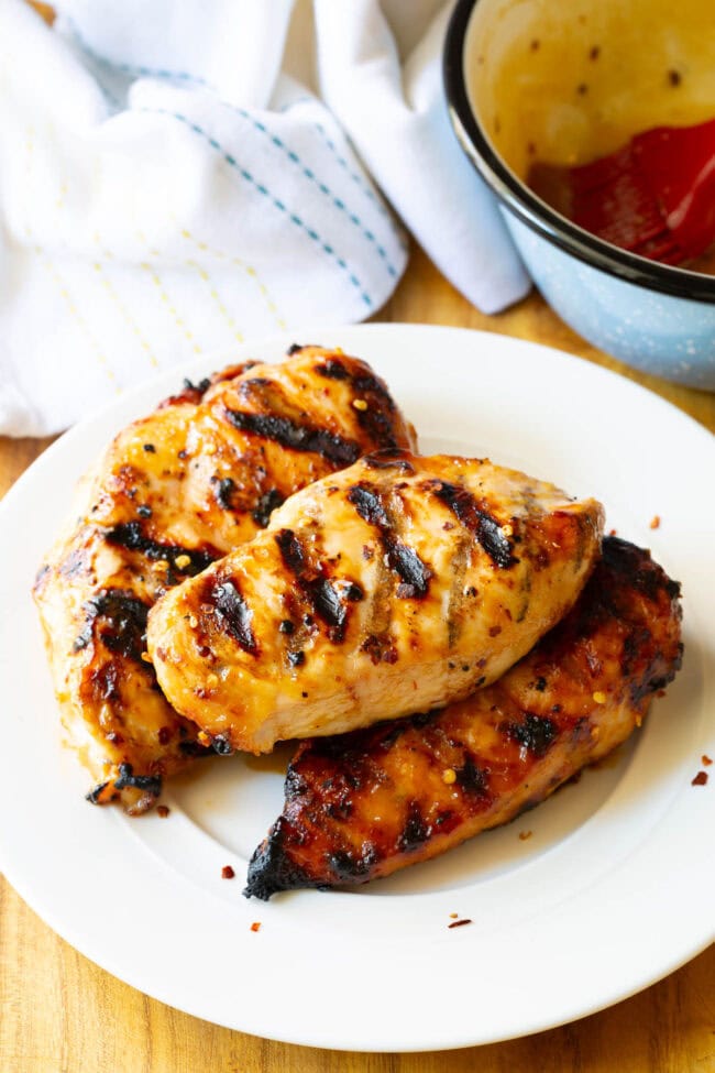 Grilled honey miso chicken stacked on a white plate.