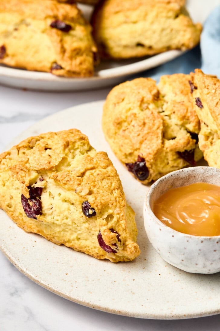 Walnut Cherry Scones on a plate with lemon curd - whole scone up front
