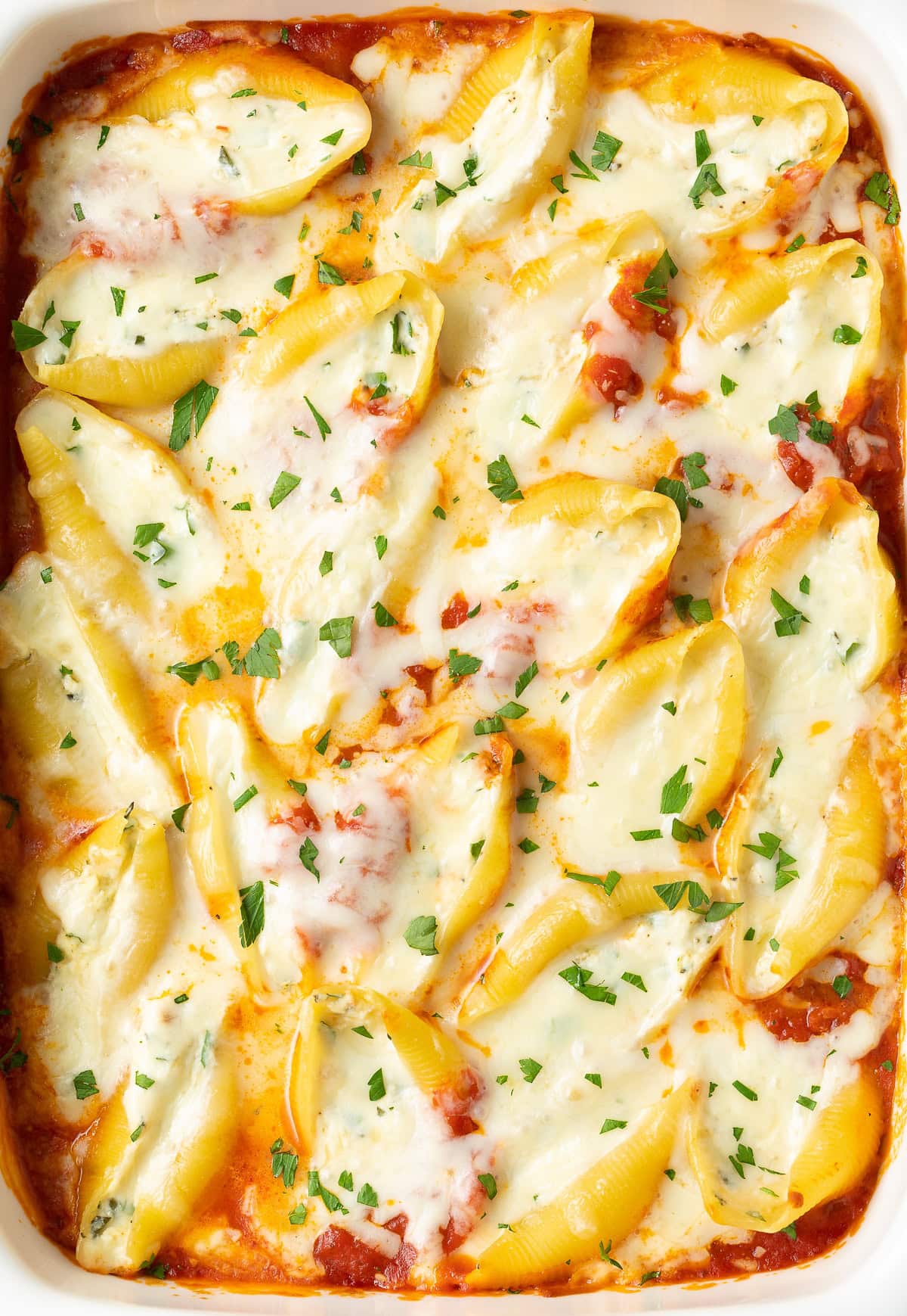 Overhead close up of a baking dish of cheesy baked ricotta stuffed shells.