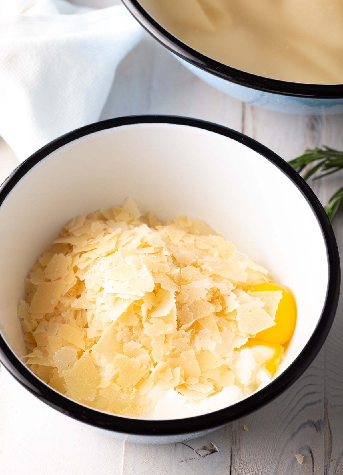 Black lipped bowl of grated cheese, ricotta and eggs.