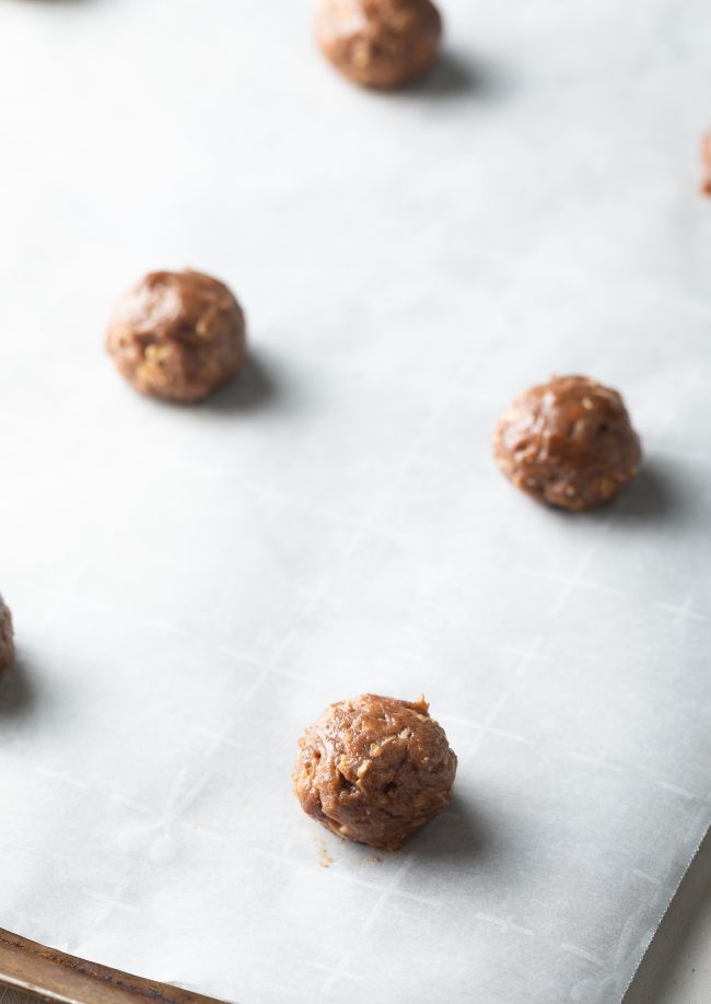 Balls of oatmeal cookie dough on parchment paper. 
