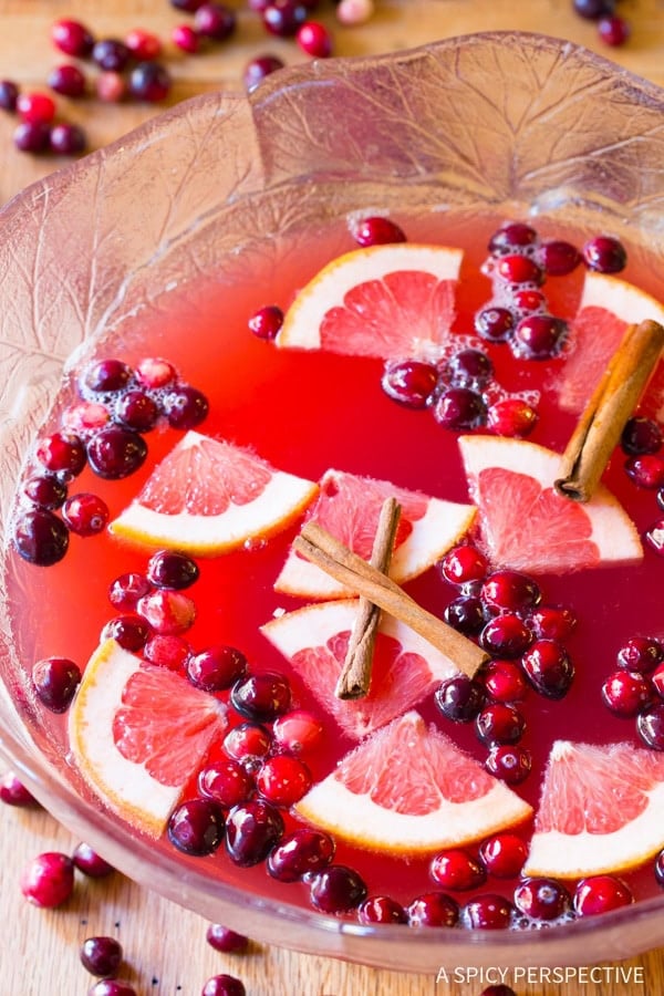 Christmas Punch Recipe with champagne - overhead shot in large glass bowl - fruit and cinnamon sticks floating on top of the punch
