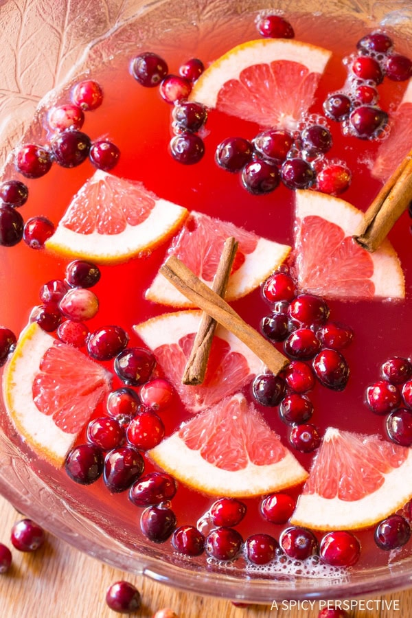 Holiday Punch #ASpicyPerspective Holiday Champagne Punch in a large punch bowl with fruit floating on top