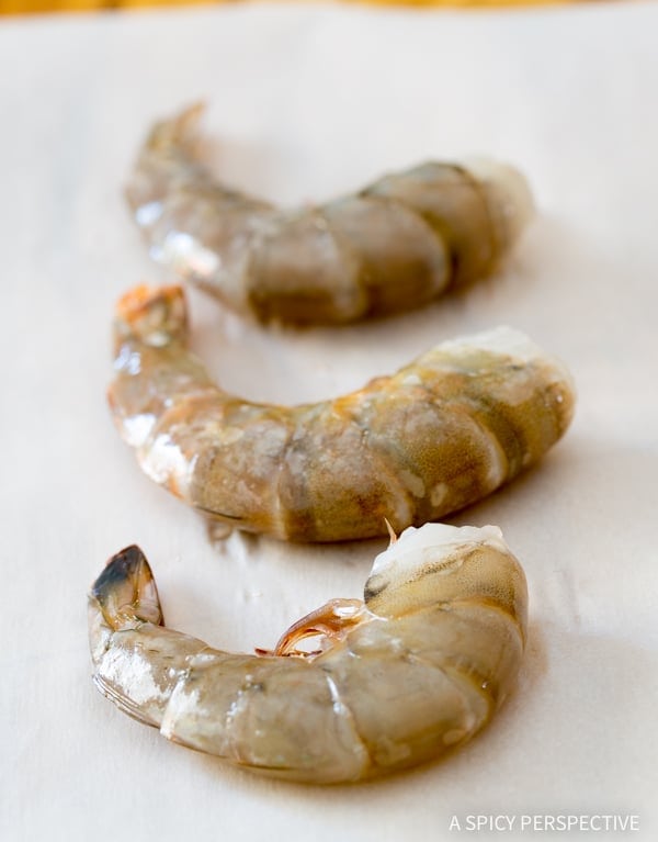 Raw shrimp on a baking sheet.