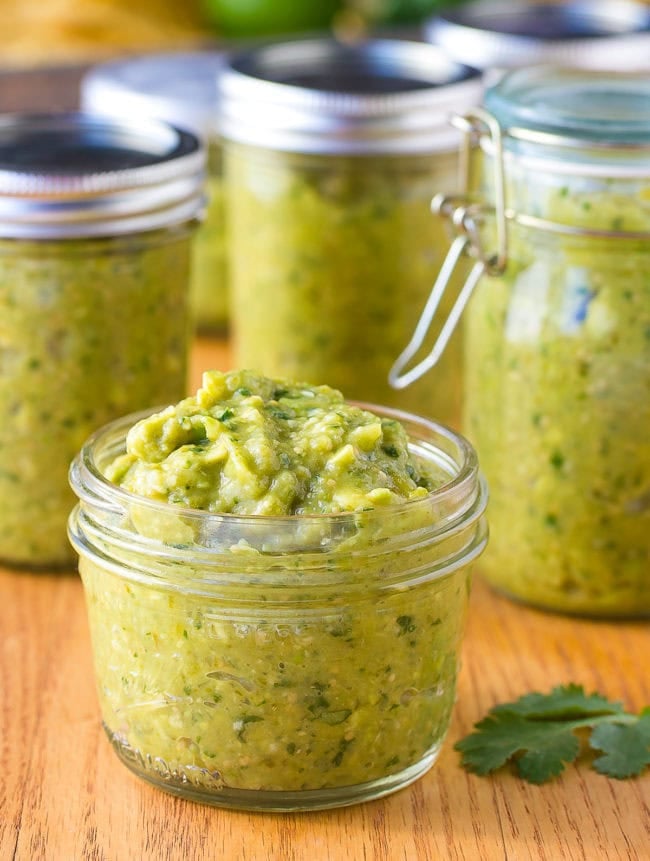 salsa verde recipe Avocado salsa verde served in a small jar with more jars of salsa in the background.