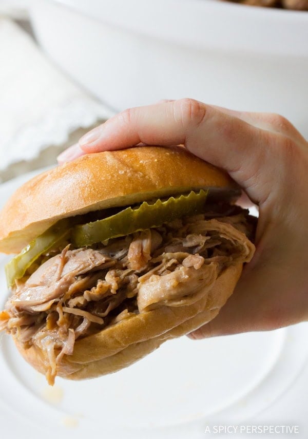 Hand holding a pulled pork sandwich.