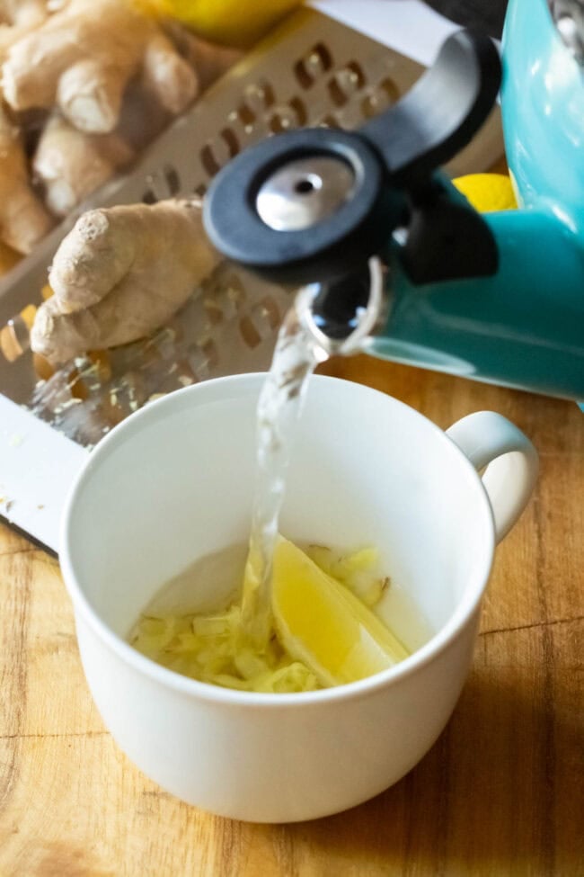 Hot water being poured over grated ginger and lemon. 