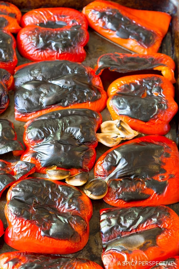 Red bell peppers on a baking sheet after being roasted. 