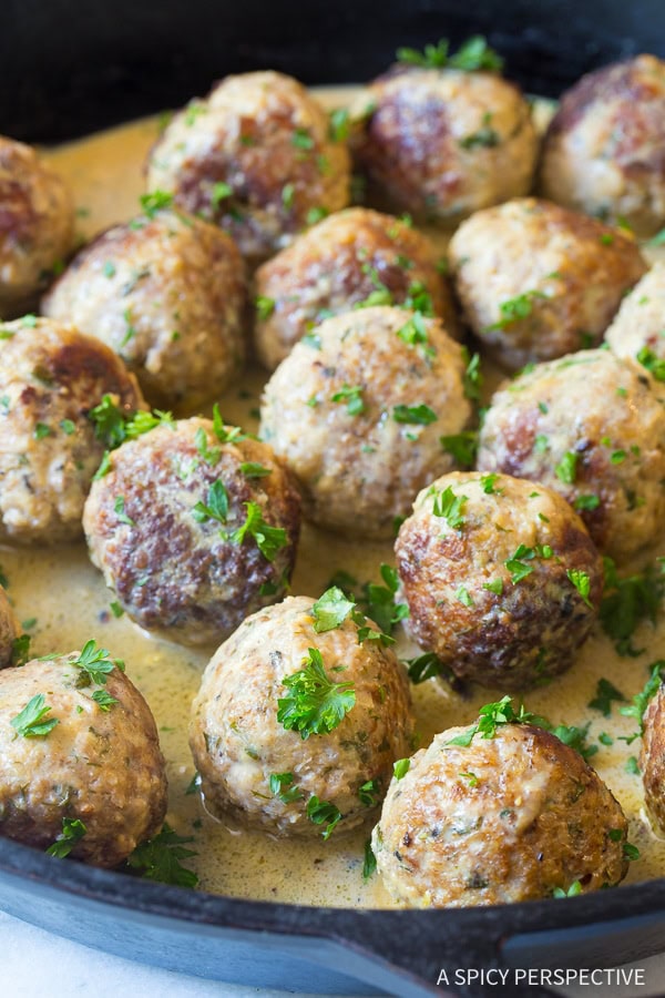 Saucy Greek Lemon Meatballs in a pan garnished with parsley.