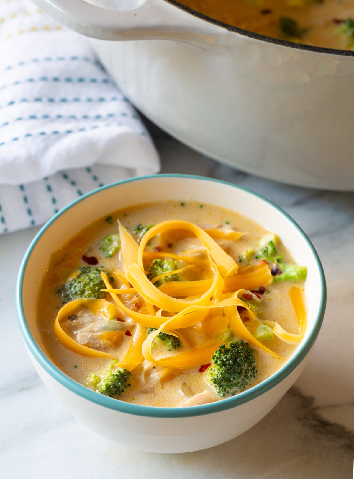 creamy broccoli soup with chicken in a bowl with extra shredded cheese