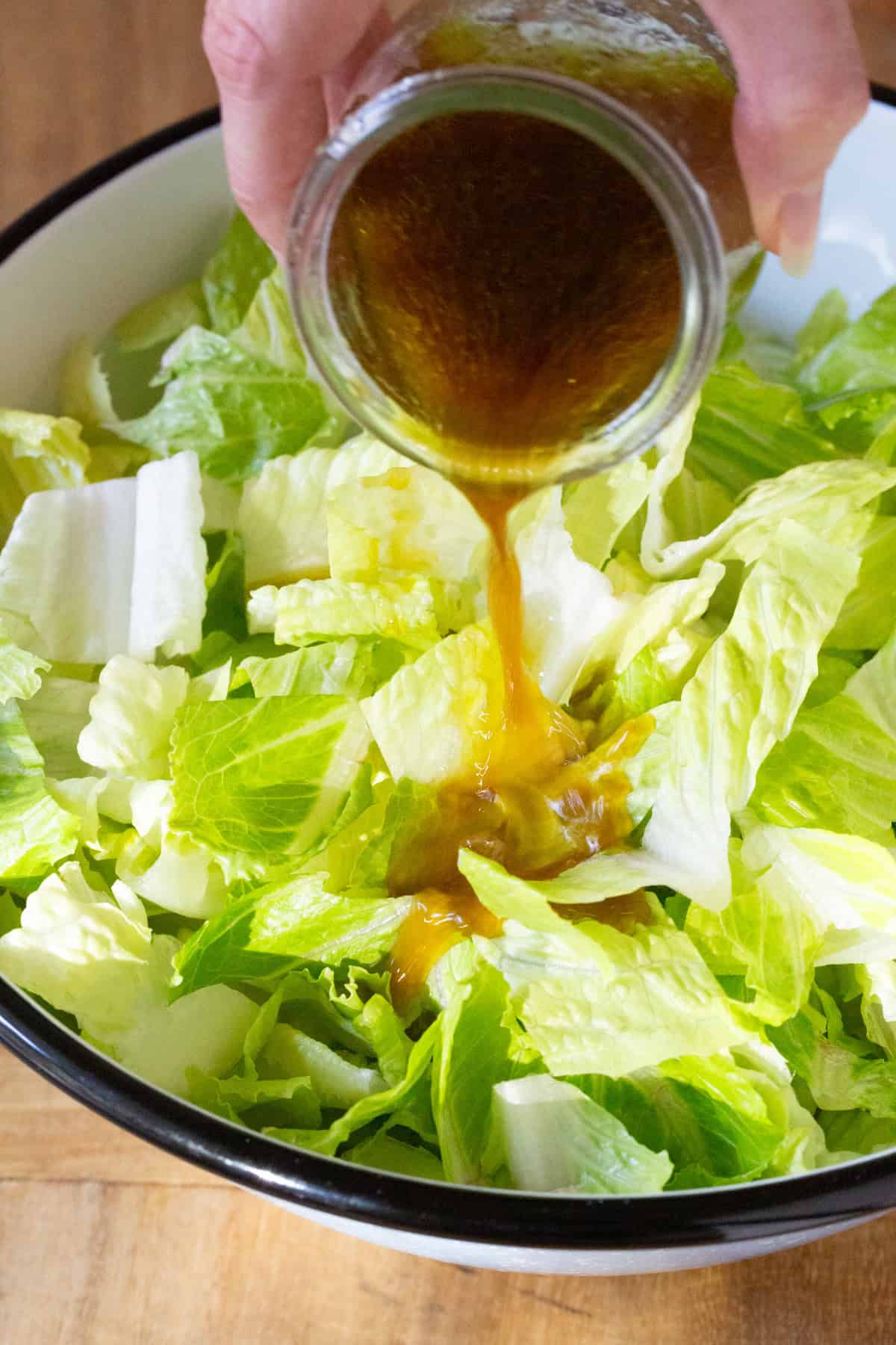 Dressing being poured over salad. 