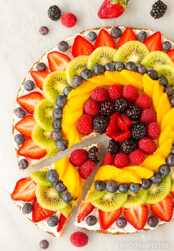 Wide overhead shot of slice being removed from vegan fruit pizza.