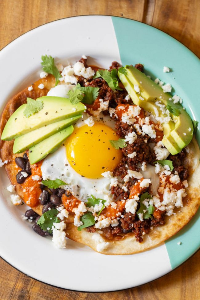Gorgeous plate full of huevos rancheros and toppings 
