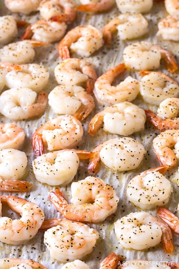 Cooked and seasoned shrimp on a baking sheet.