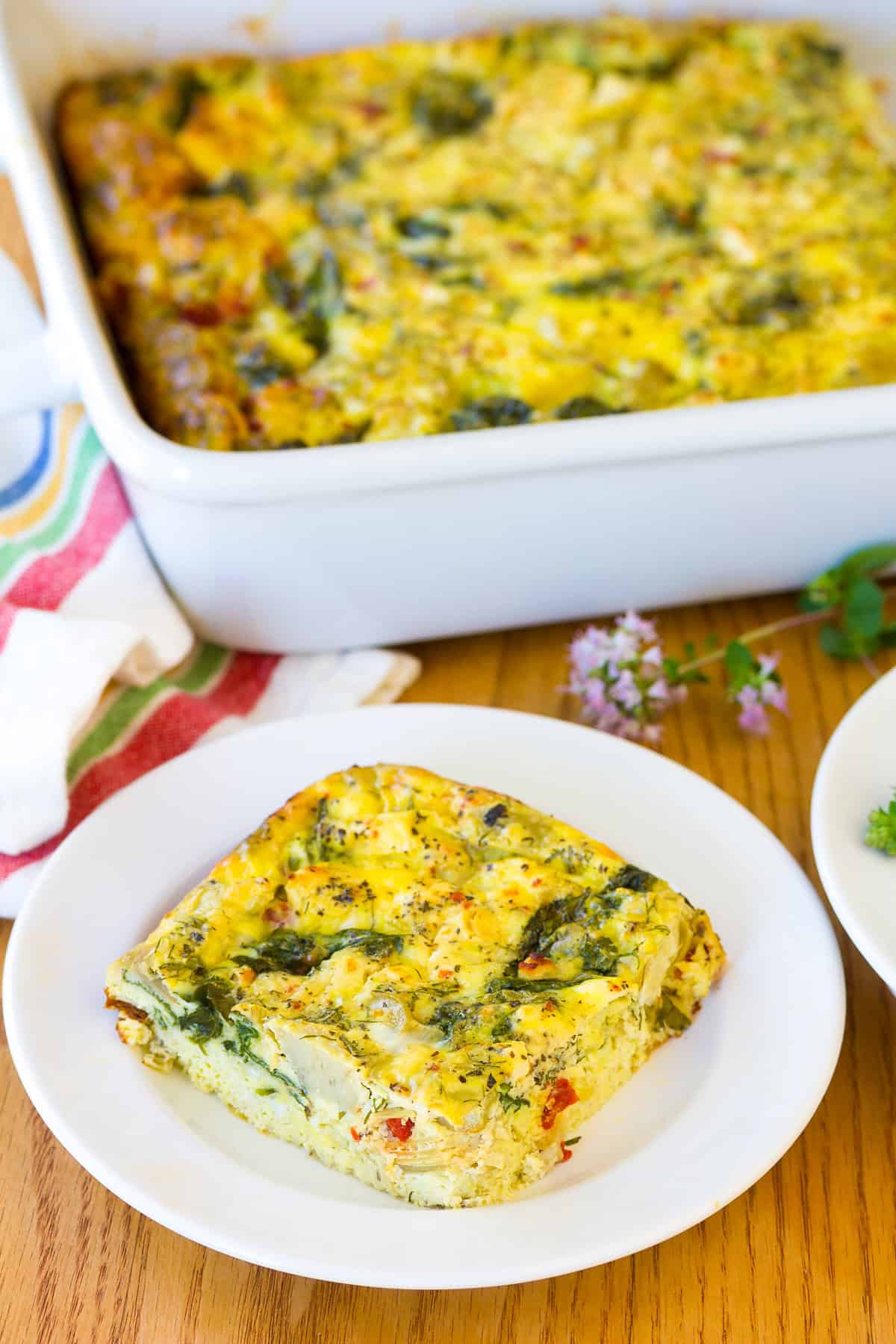 Greek Omelette Casserole cut on plate with baking dish in background