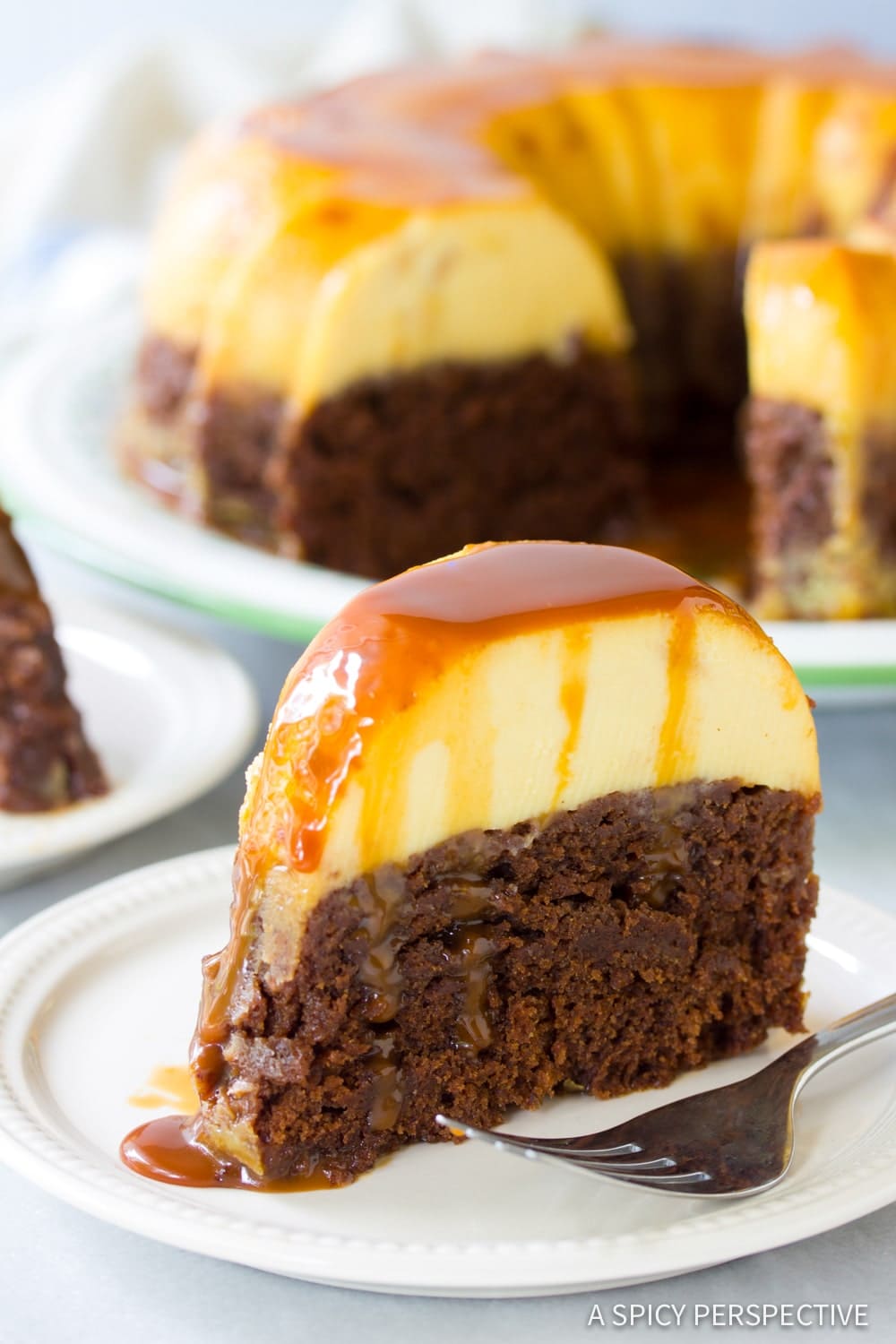 Slice of chocoflan cake on a white plate with a fork. 