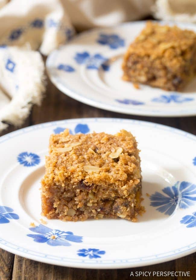 Single slice of breakfast oatmeal bar recipe on a plate with nuts and dates visible.