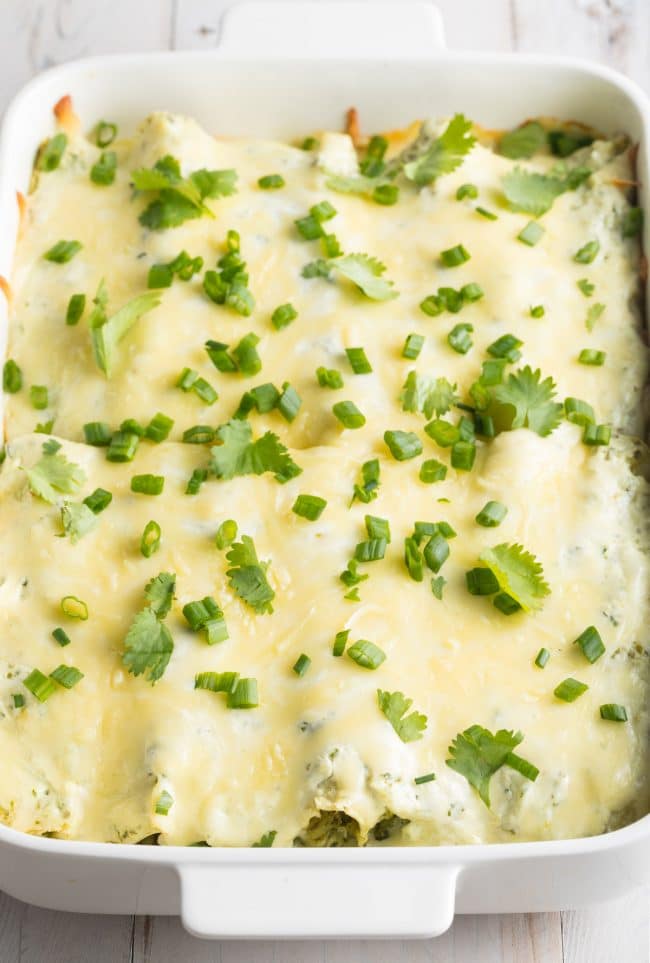 Baked Enchilada Suiza in a white pan covered with fresh cilantro and scallion garnish. 