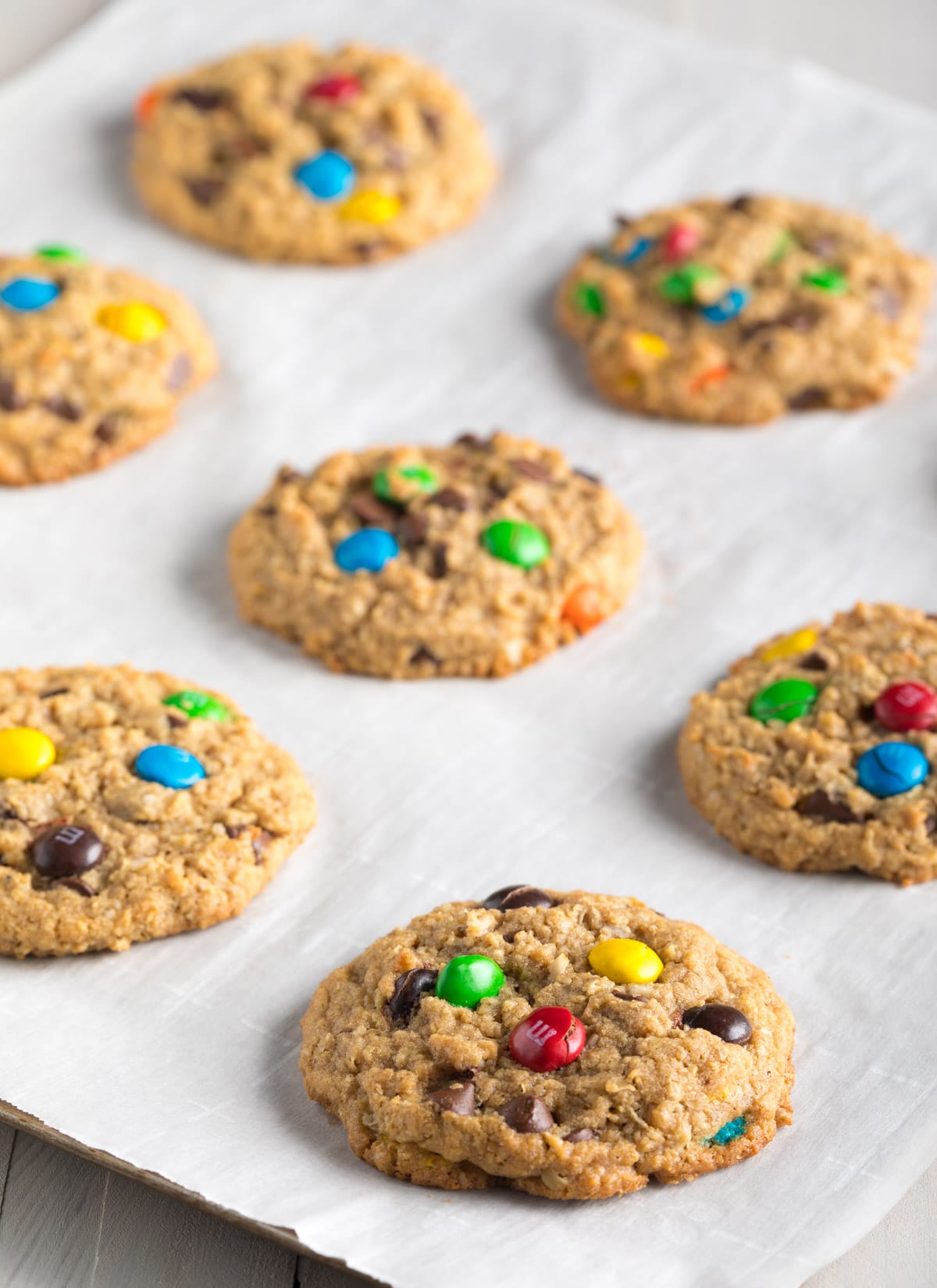 Baking sheet with 9 baked peanut butter oatmeal cookies with m&ms.