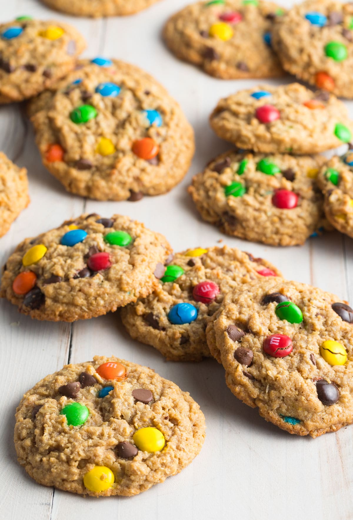 A dozen peanut butter oatmeal monster cookies with m&m candies, in small groups of 3-4 cookies.