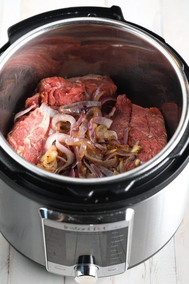 Meat and onions in the pressure cooker before being cooked. 
