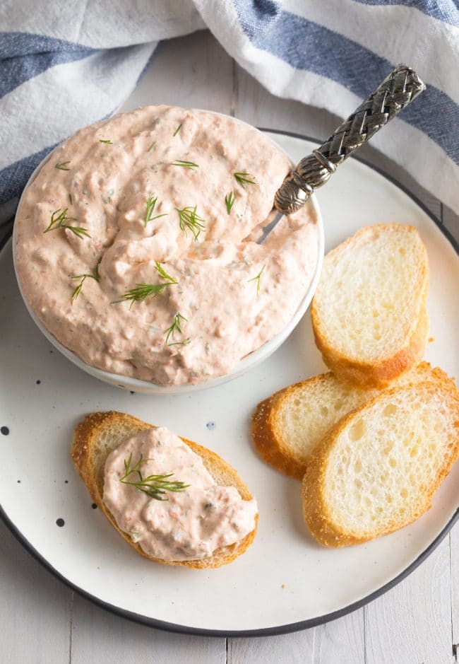 Small pieces of toasted bread with salmon dip on the tip
