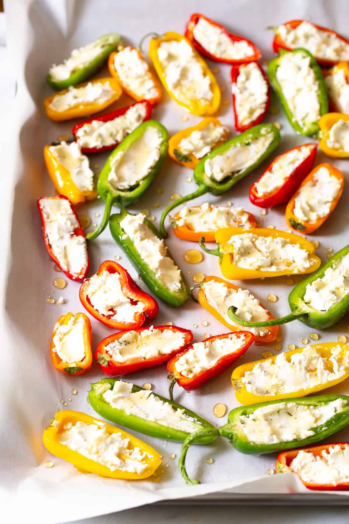 bell peppers stuffed w ith cheese on a baking tray