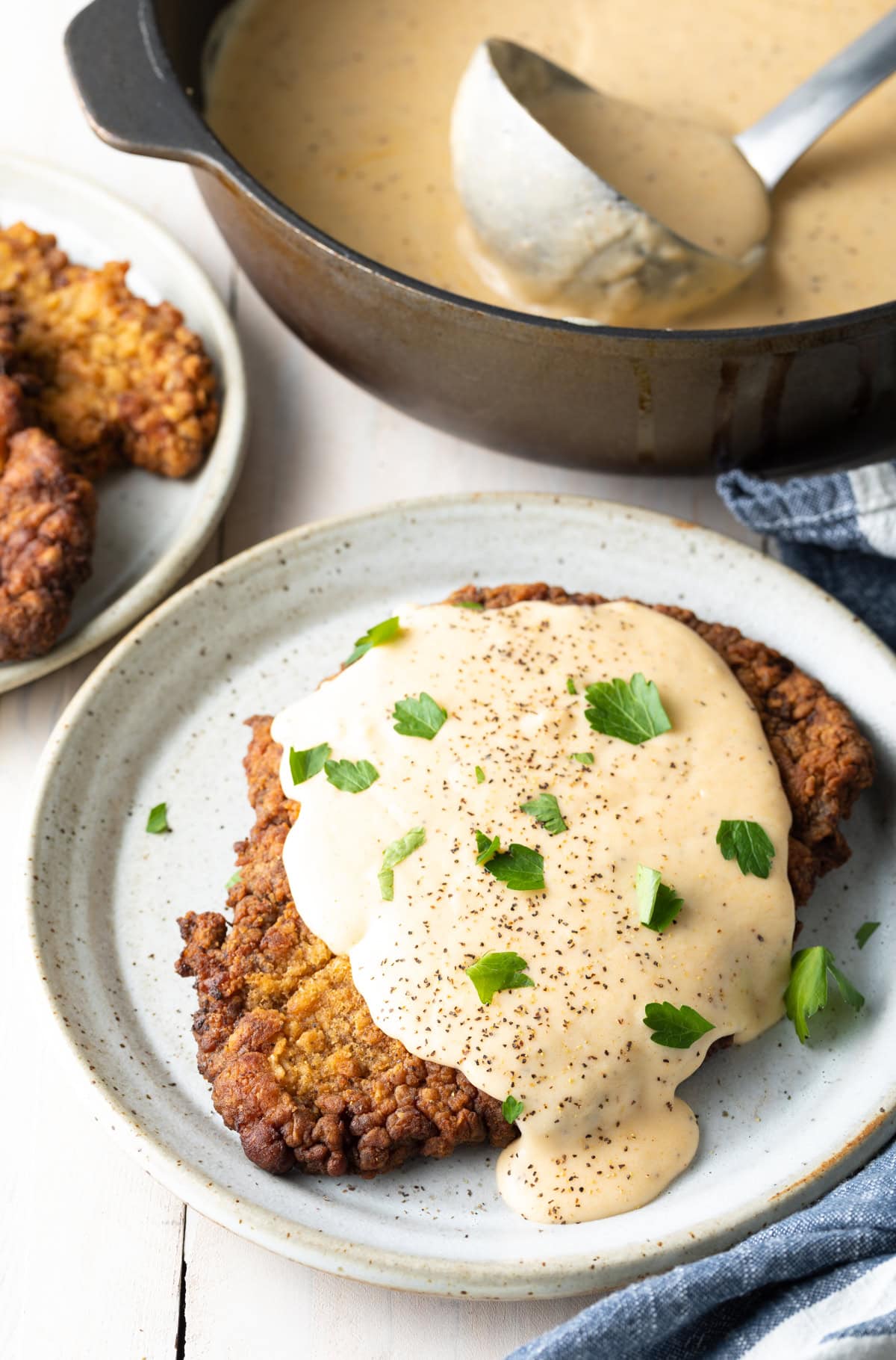 Plated chicken fried steak covered with white gravy.
