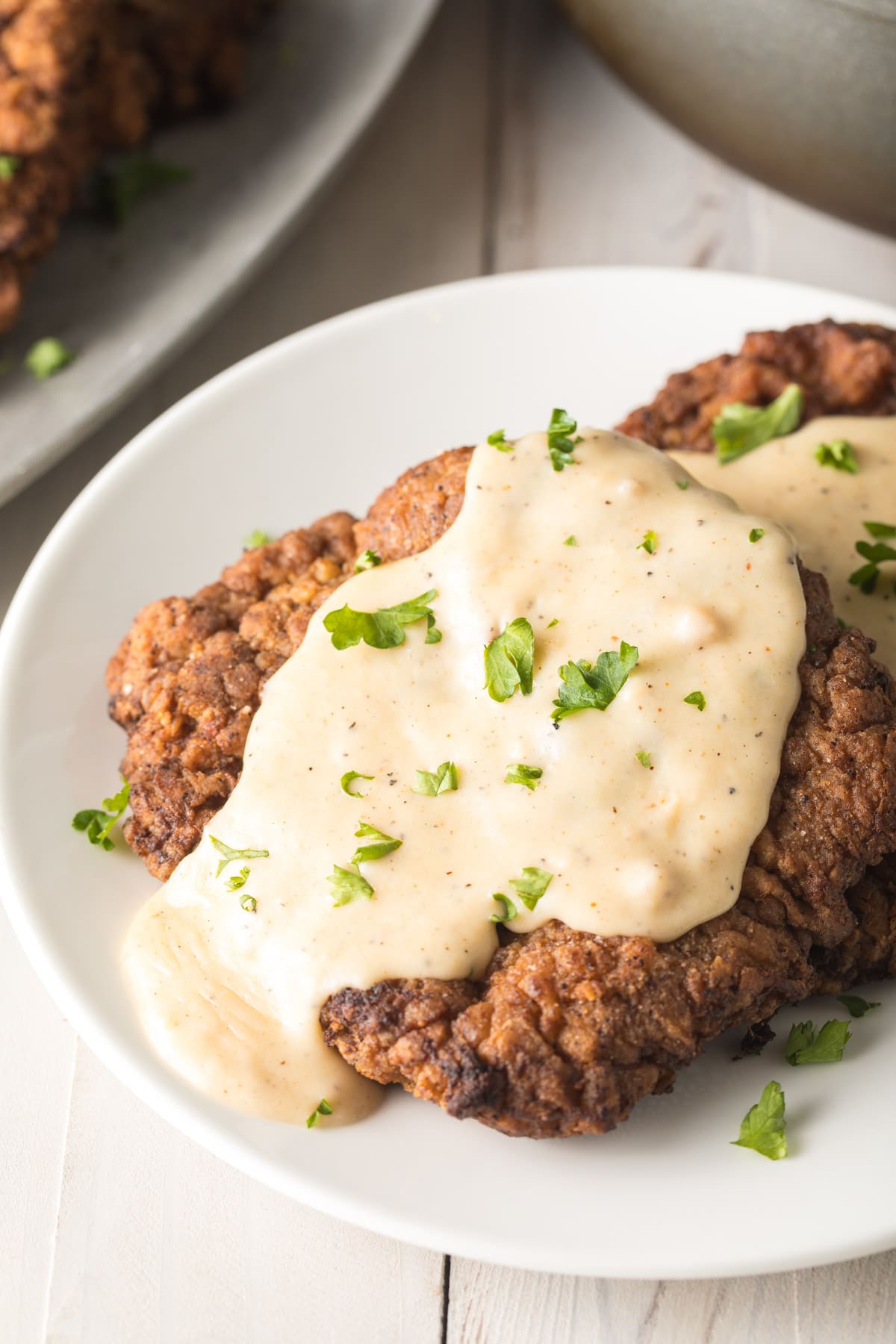 Fried steak covered in gravy on a plate.