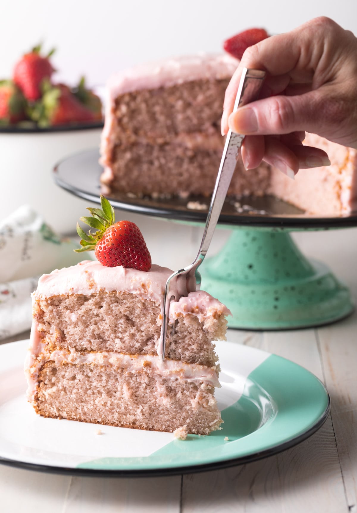 Hand with fork taking a piece from slice of cake. 