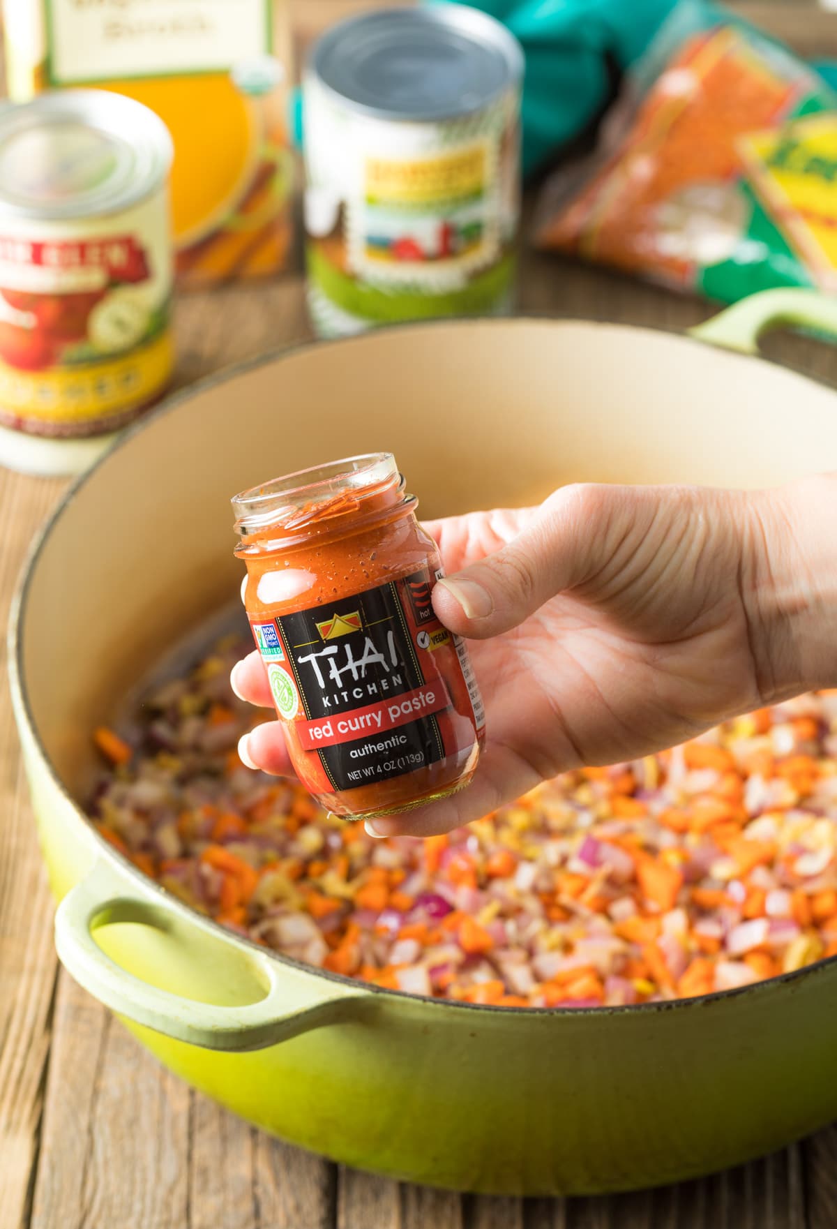 Hand holding jar of Thai Red Curry Paste to camera.