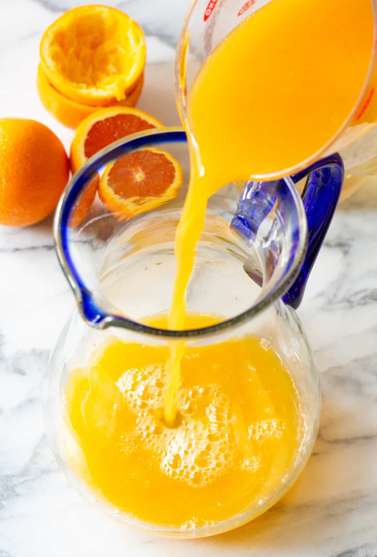 pouring fresh orange juice into large pitcher