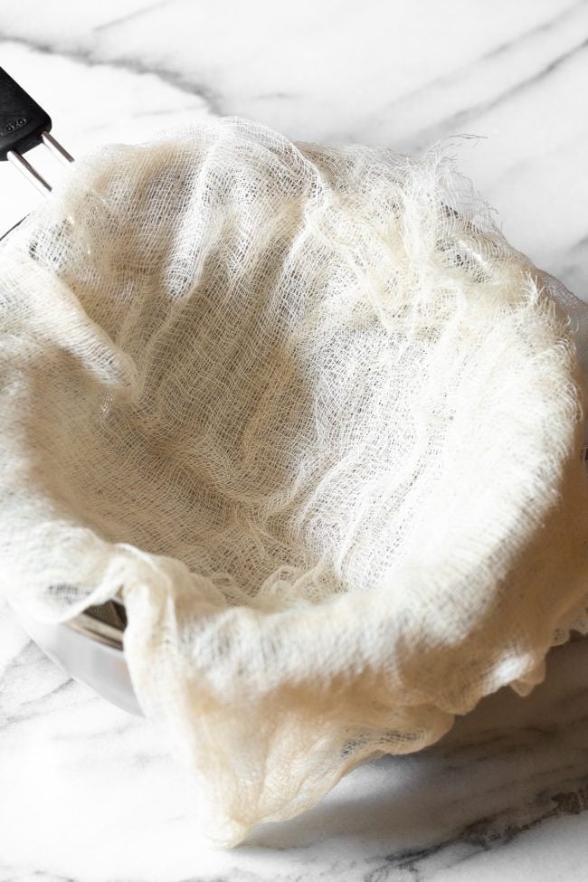 Cheesecloth laid over a metal bowl.