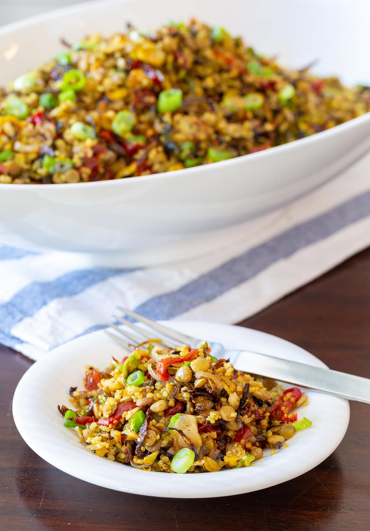 quinoa lentil salad.  Side photo in white bowl with plate and fork filled with quinoa lentil salad.  