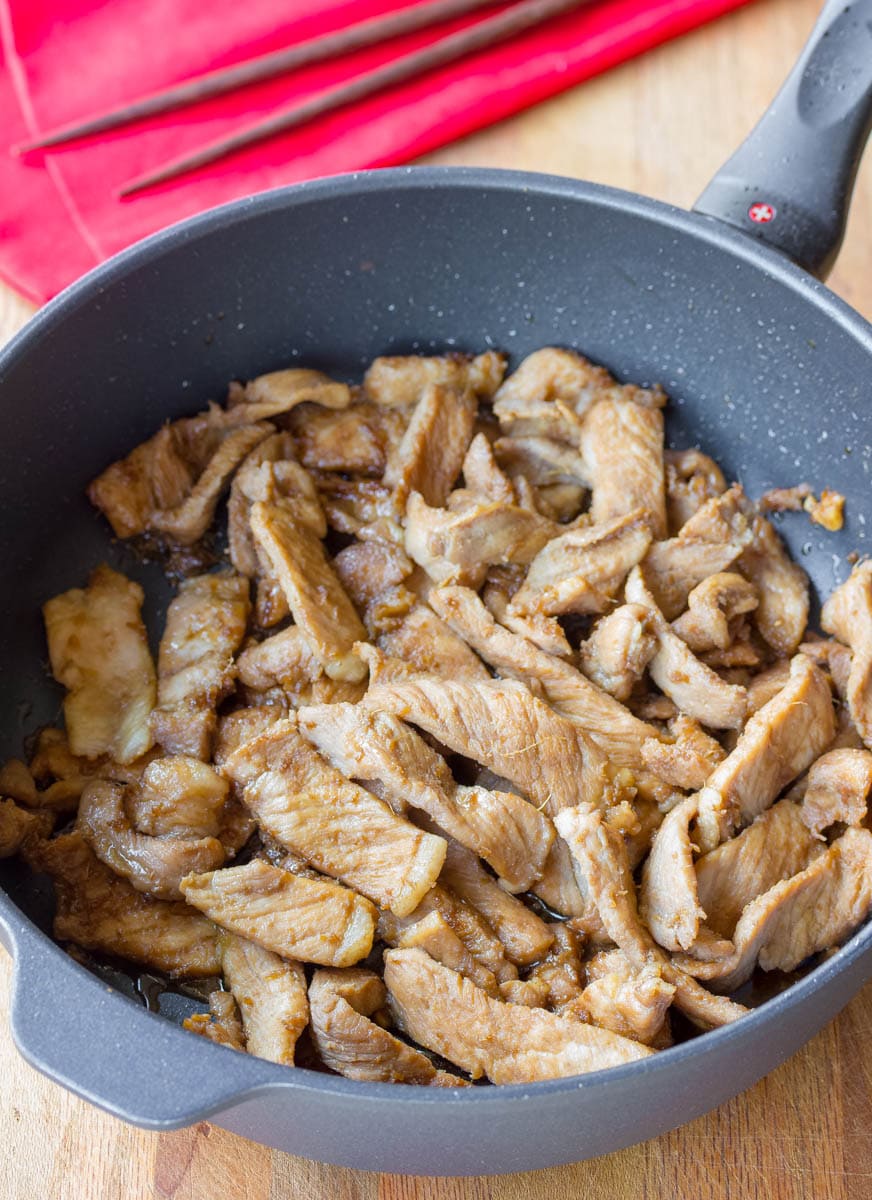Top down view of pork being fried in a skillet.