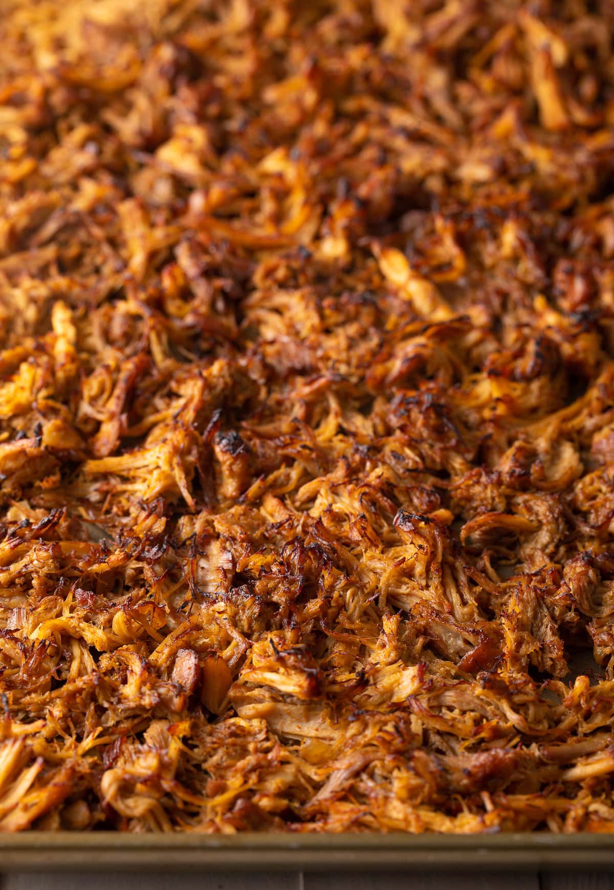 Shredded carnitas on a baking sheet that was broiled.